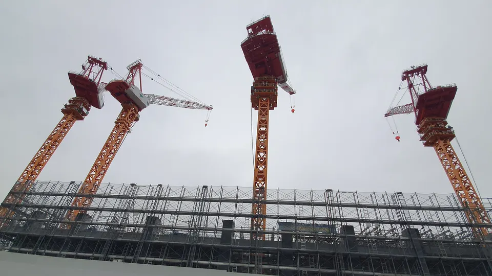 足場を組んだ建設現場とタワークレーンの写真